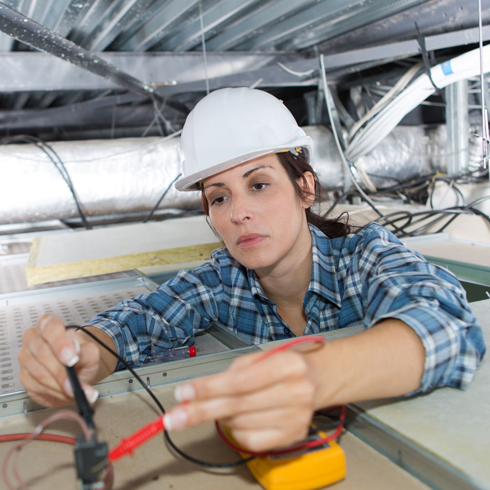Female electrician calibrating ceiling lamps